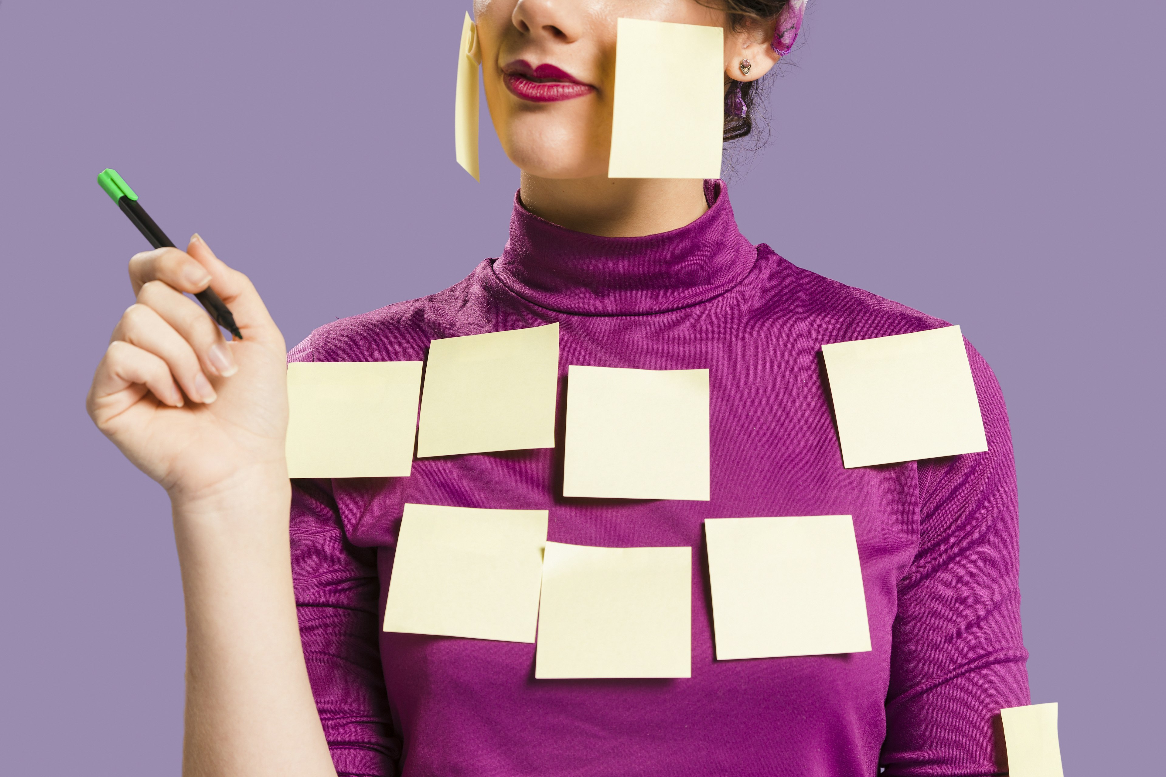 Donna con post-it sul viso e sul corpo, simbolo di brainstorming e pianificazione strategica, su sfondo viola. Concetto di organizzazione e creatività aziendale
