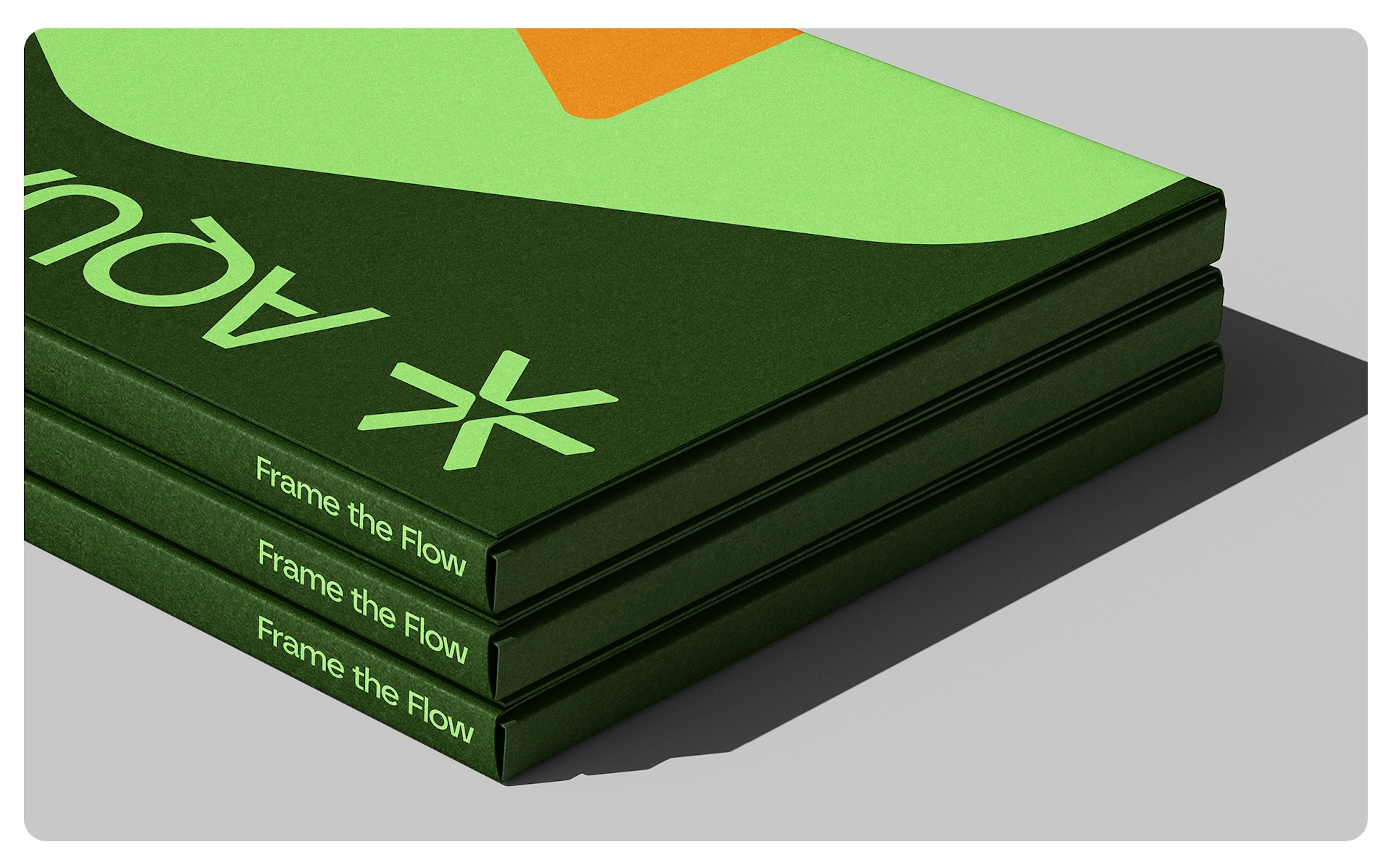 A stack of three green books with the title 'Frame the Flow' on the spines, featuring a modern design with abstract shapes and the 'AQUADRA' logo on the cover