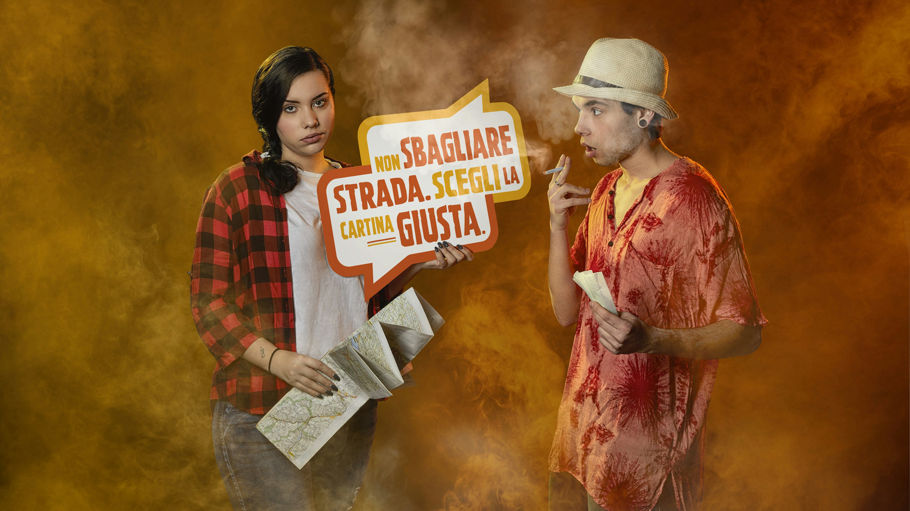 A young woman holding a map stands next to a man smoking a cigarette, both in a smoky orange background. She holds a sign that says, "Non sbagliare strada. Scegli la cartina giusta," highlighting a message about making the right choices.